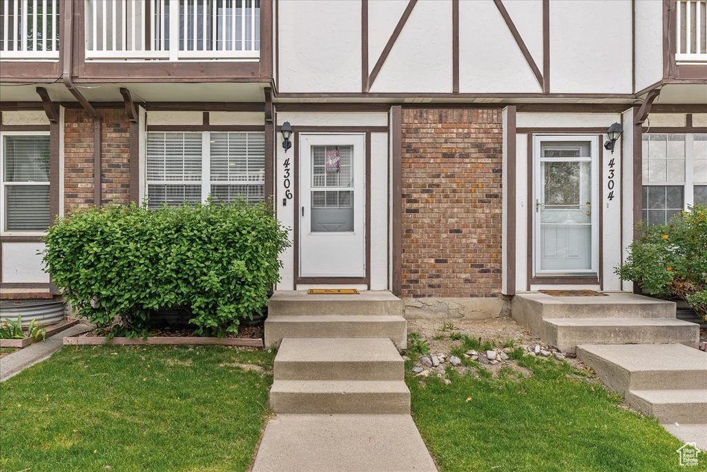 Doorway to property featuring brick siding, stucco siding, and a balcony