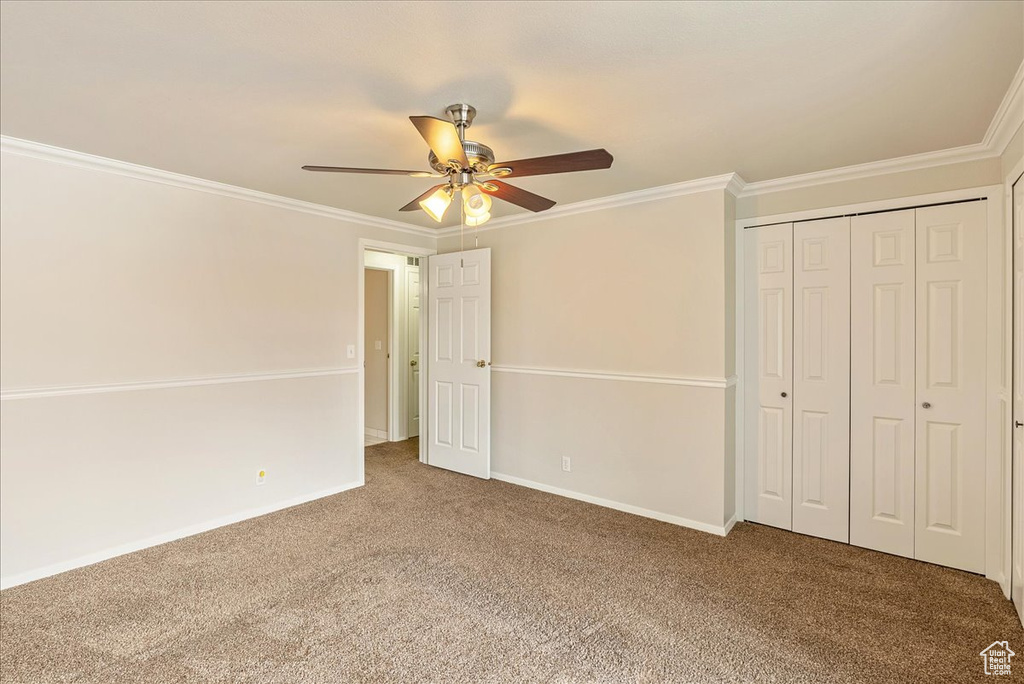 Unfurnished bedroom with a closet, baseboards, ornamental molding, and carpet flooring
