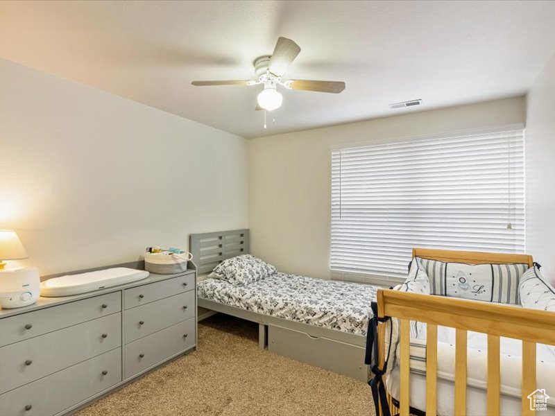 Bedroom featuring visible vents, a ceiling fan, and light colored carpet