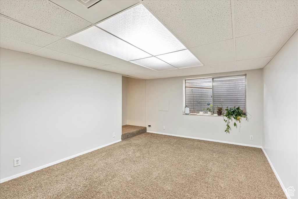 Carpeted spare room featuring baseboards and a paneled ceiling