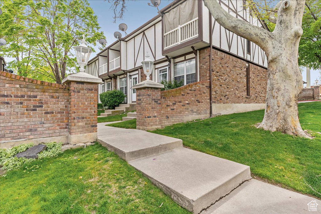 Exterior space with a balcony, a yard, and brick siding