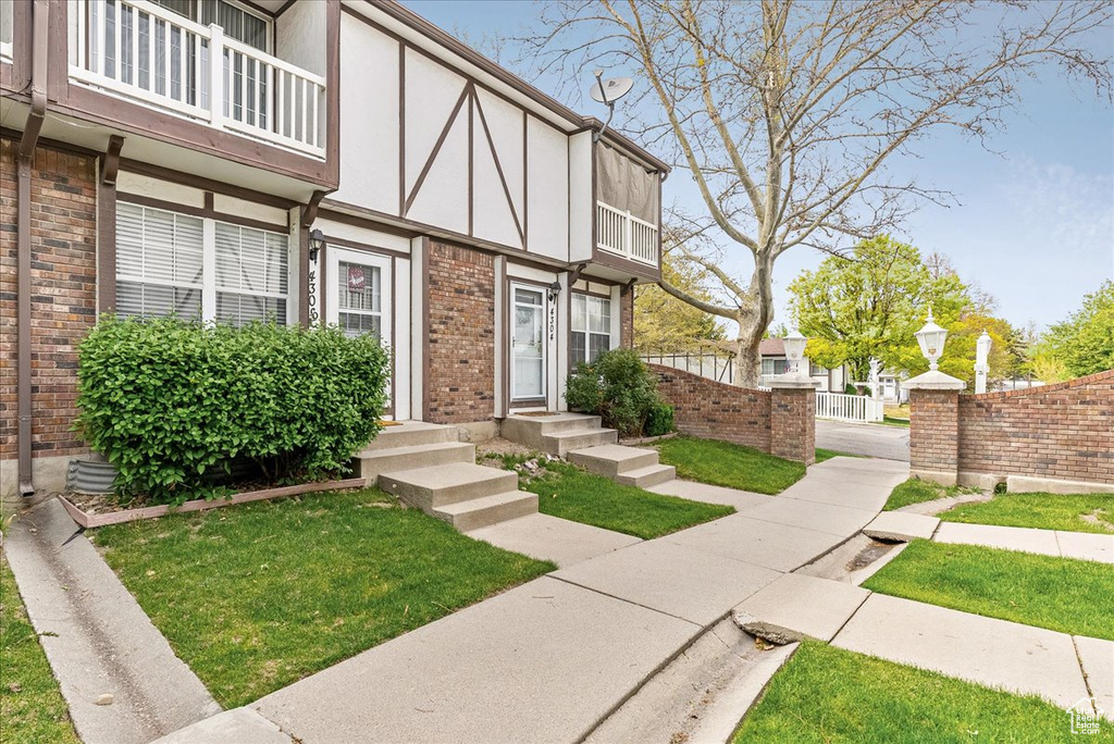 View of exterior entry featuring brick siding, stucco siding, fence, and a balcony