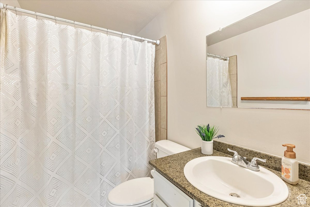 Bathroom with toilet, curtained shower, and vanity