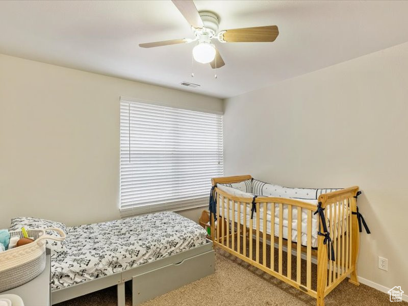 Carpeted bedroom featuring visible vents, a ceiling fan, and baseboards