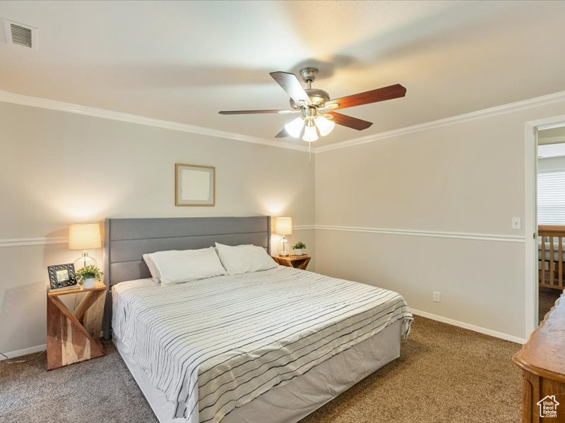 Bedroom featuring visible vents, carpet, crown molding, and baseboards