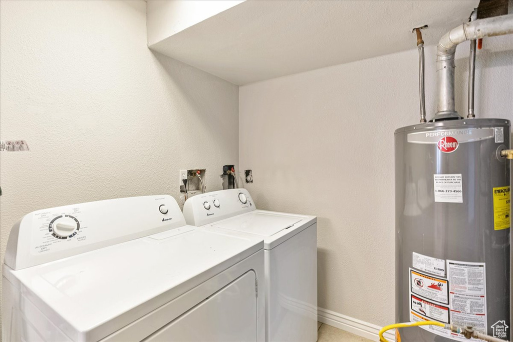 Laundry room with water heater, laundry area, and washing machine and clothes dryer