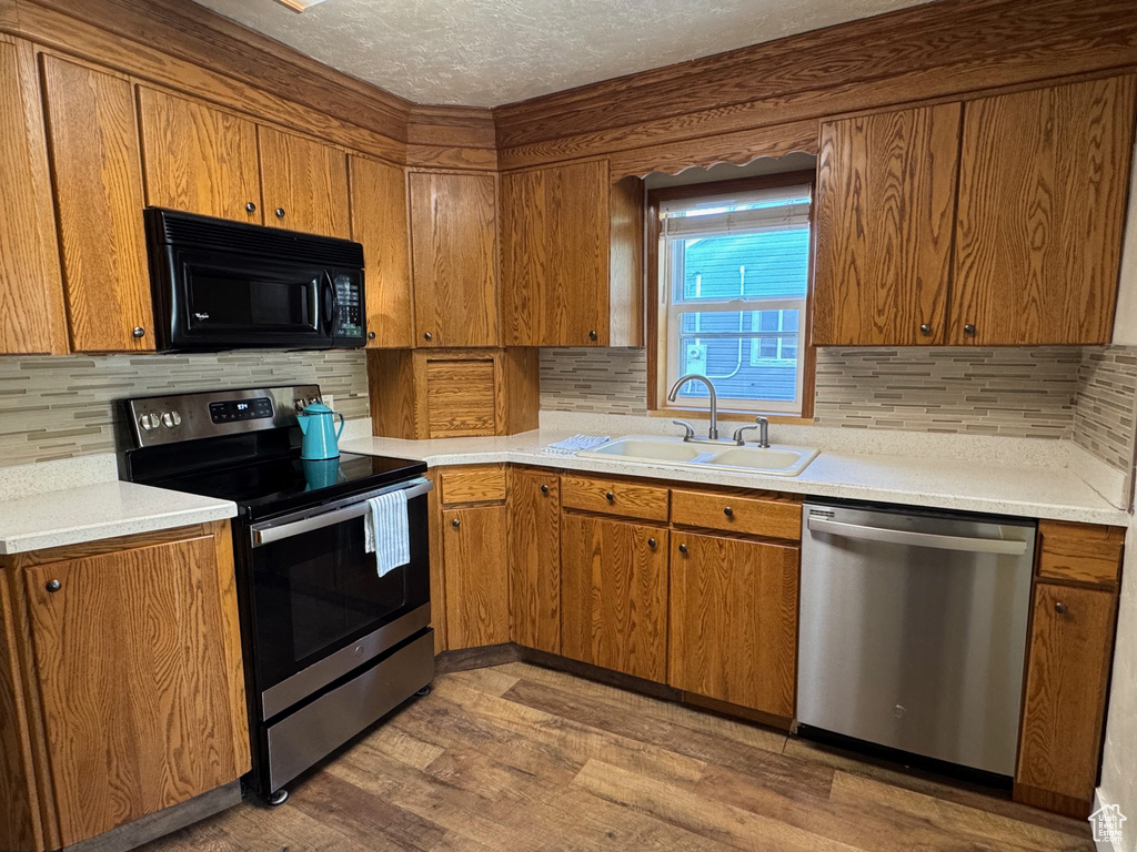 Kitchen featuring brown cabinetry, a sink, light wood-style flooring, and stainless steel appliances