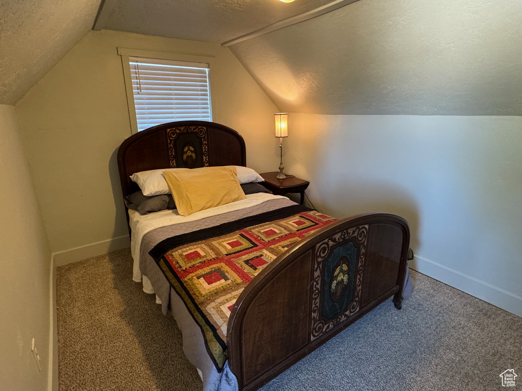 Carpeted bedroom with baseboards, a textured ceiling, and vaulted ceiling