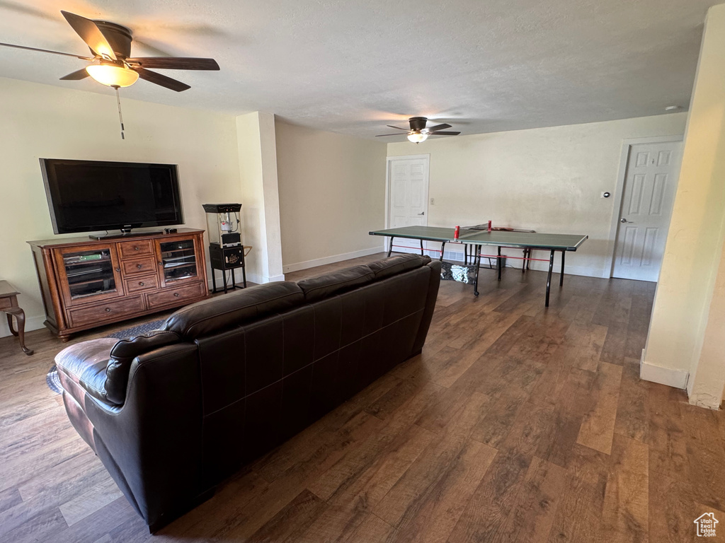 Living room with baseboards, ceiling fan, and dark wood-style floors