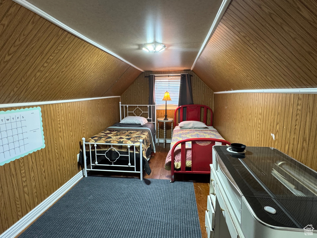 Bedroom with wood walls, wood finished floors, and vaulted ceiling