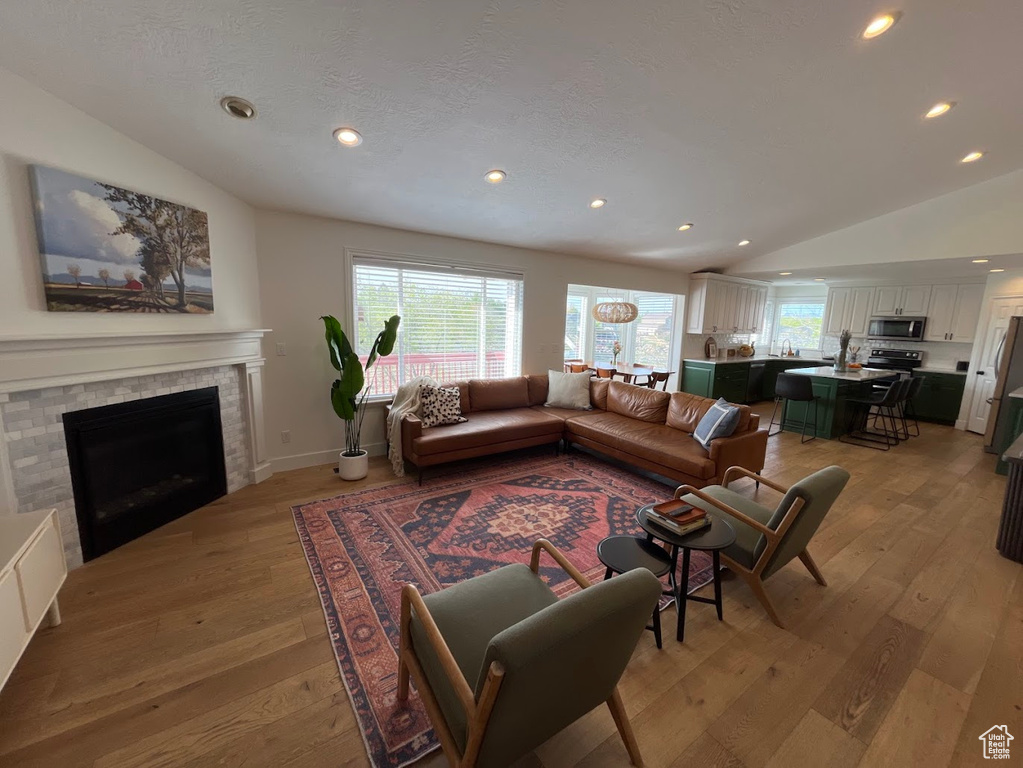 Living room featuring light wood-style floors, plenty of natural light, vaulted ceiling, and recessed lighting