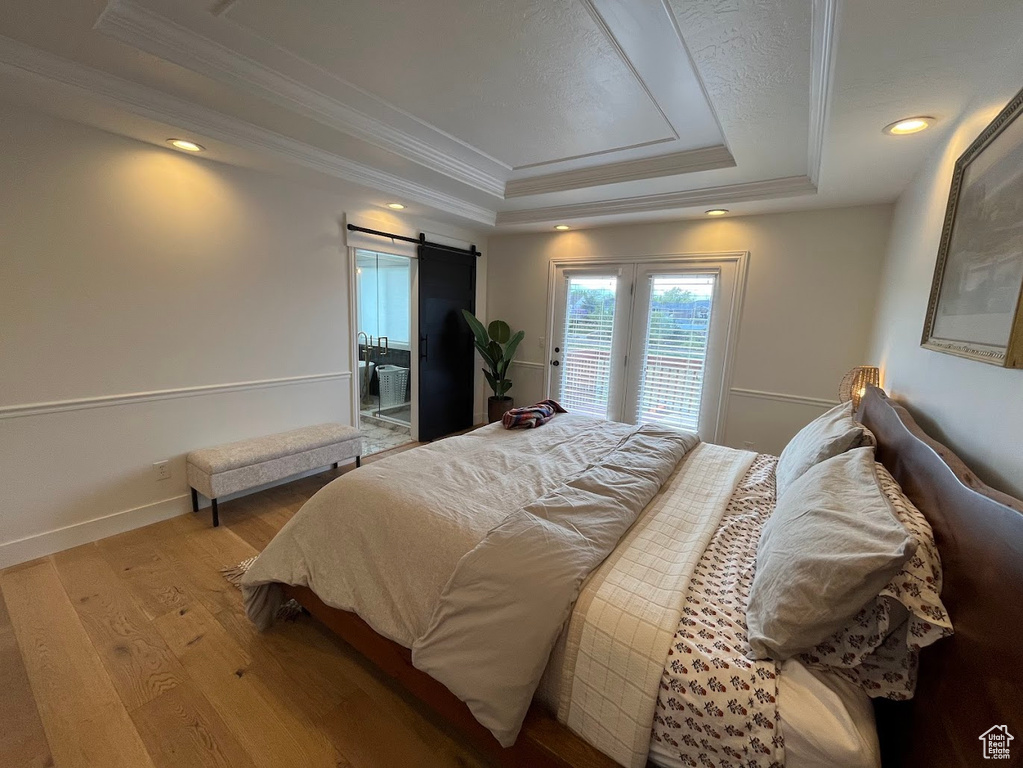 Bedroom featuring access to outside, a barn door, crown molding, and a tray ceiling
