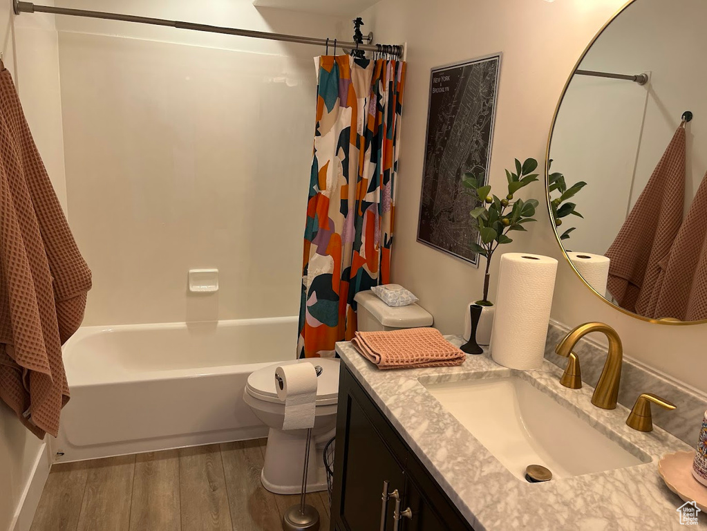 Bathroom featuring vanity, toilet, wood finished floors, and shower / tub combo with curtain