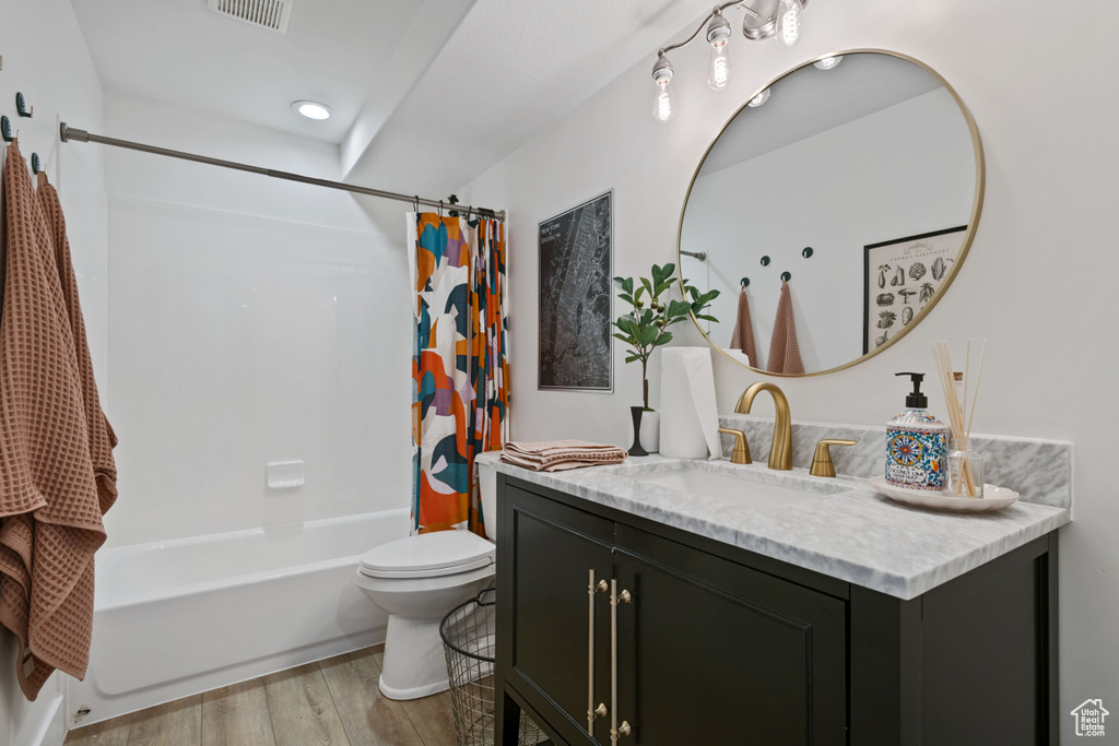 Bathroom with wood finished floors, shower / bath combo with shower curtain, toilet, vanity, and recessed lighting
