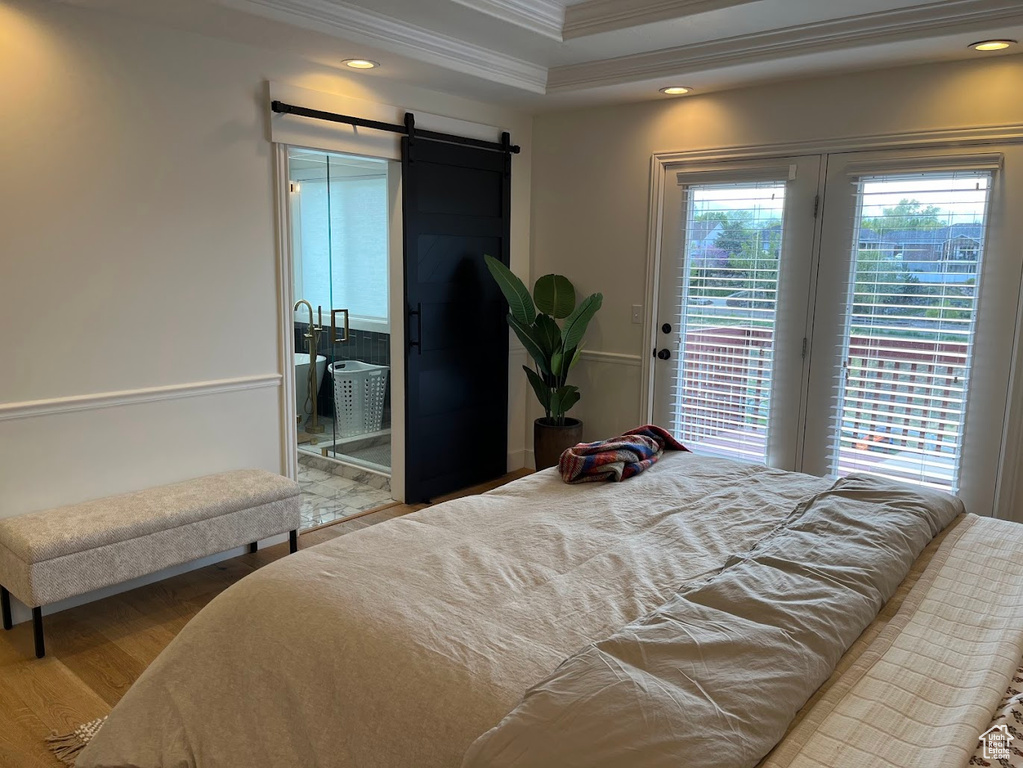 Bedroom with access to exterior, crown molding, wood finished floors, a barn door, and recessed lighting
