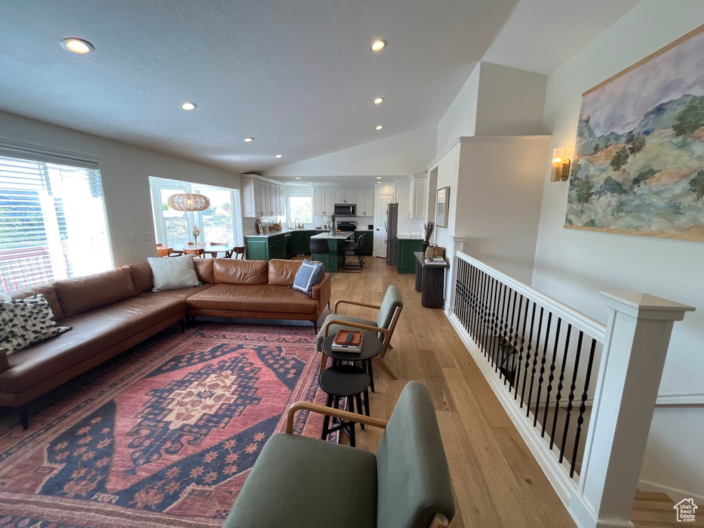 Living room with recessed lighting, light wood finished floors, and vaulted ceiling