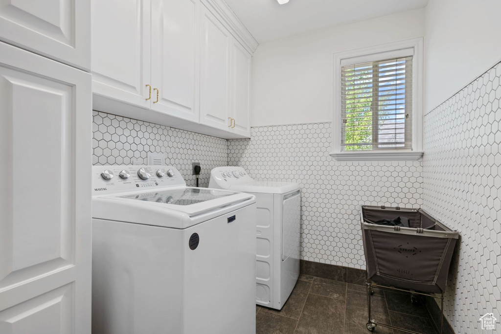 Washroom with cabinet space, independent washer and dryer, and baseboards