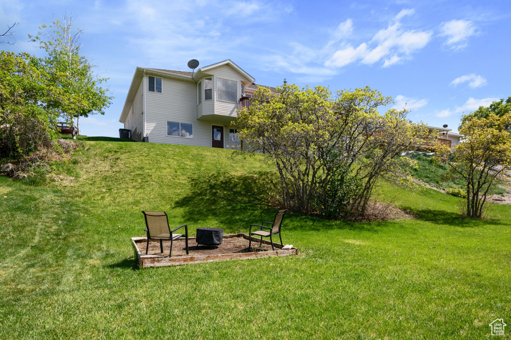 View of green lawn featuring a fire pit