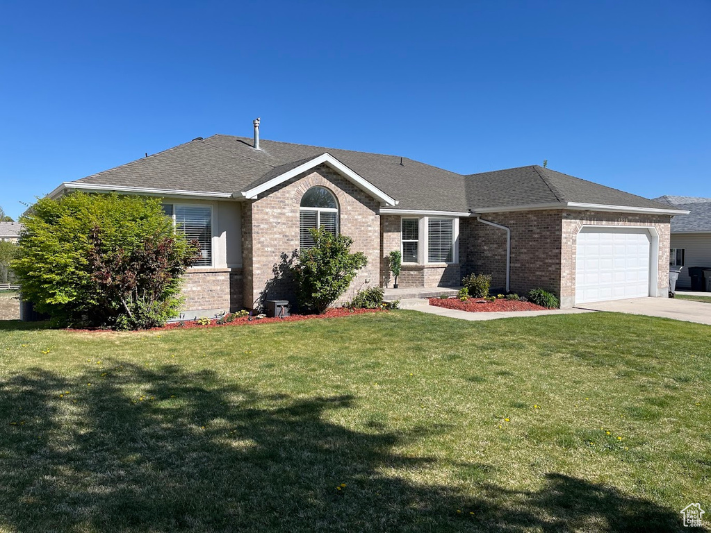 Single story home featuring roof with shingles, a front lawn, brick siding, a garage, and concrete driveway