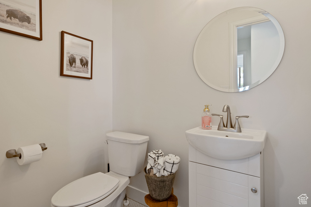 Half bathroom featuring toilet, vanity, and baseboards
