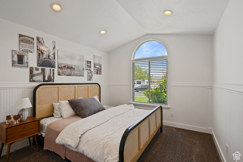 Bedroom with wainscoting, lofted ceiling, dark colored carpet, and recessed lighting