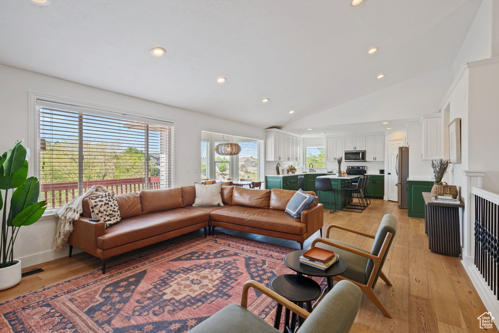 Living room with lofted ceiling, light wood finished floors, and recessed lighting