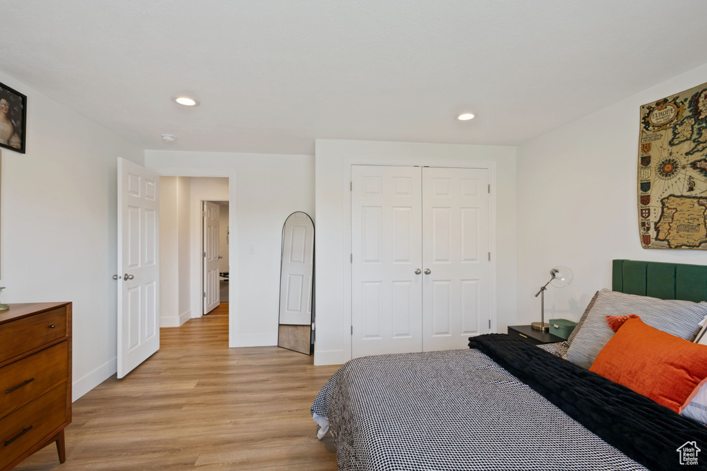 Bedroom with light wood finished floors, a closet, recessed lighting, and baseboards