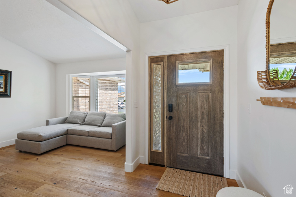 Entryway featuring light wood-style flooring, lofted ceiling, and baseboards