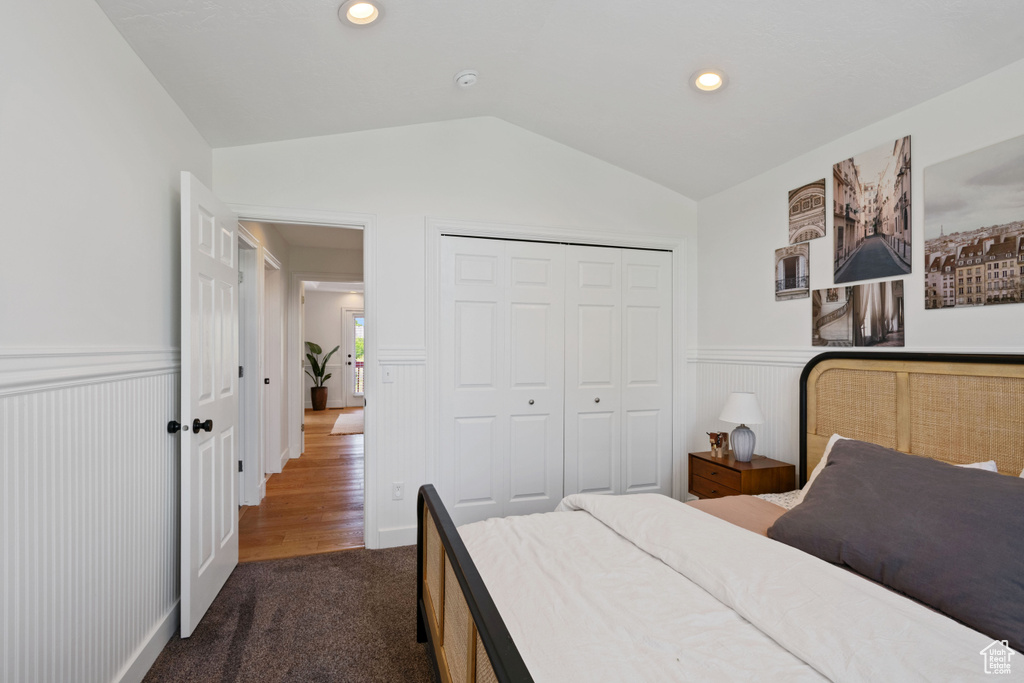 Bedroom with wainscoting, vaulted ceiling, dark colored carpet, a closet, and recessed lighting