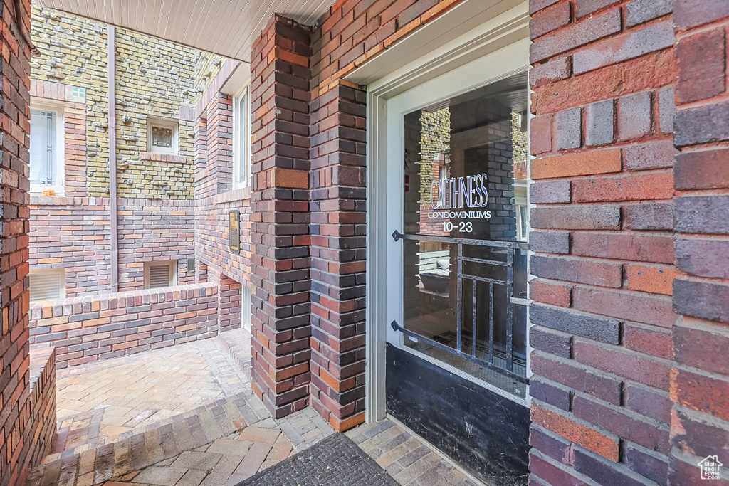 Property entrance featuring covered porch and brick siding