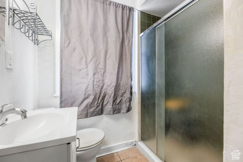 Bathroom with tile patterned flooring, vanity, toilet, baseboards, and a shower stall