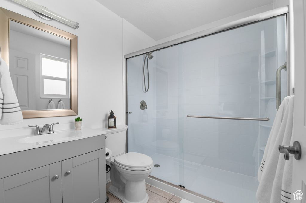 Bathroom featuring toilet, a shower stall, tile patterned flooring, and vanity