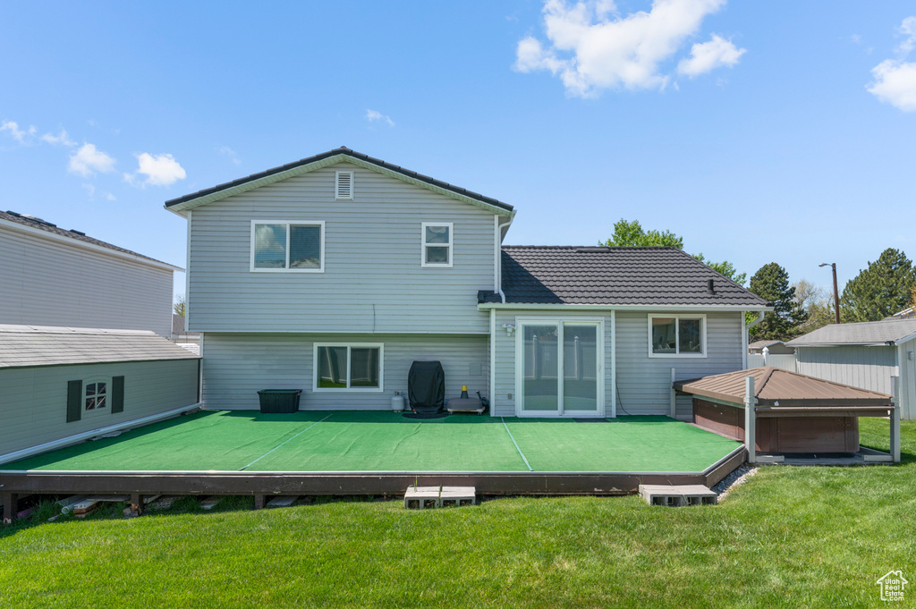 Rear view of property with a lawn and a deck