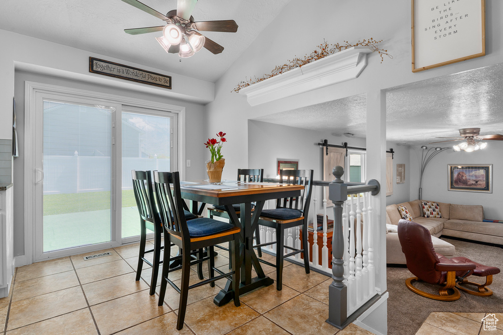 Dining area featuring a healthy amount of sunlight, ceiling fan, light tile patterned flooring, and a barn door