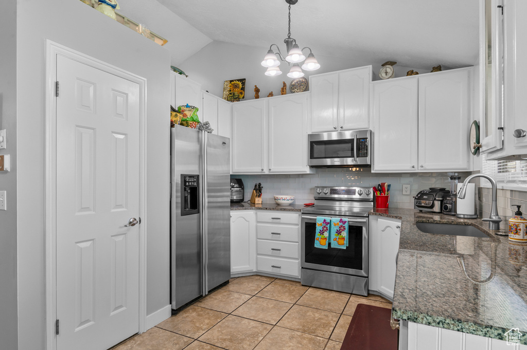 Kitchen with decorative backsplash, a sink, white cabinets, lofted ceiling, and stainless steel appliances
