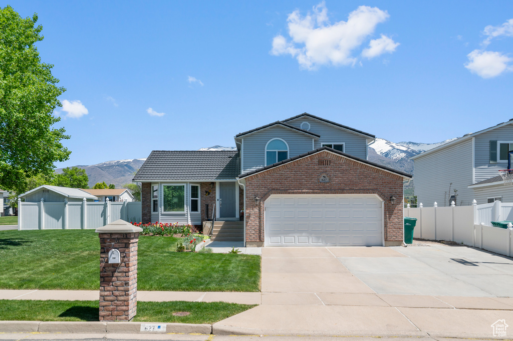 View of front of property with fence, a mountain view, an attached garage, and brick siding
