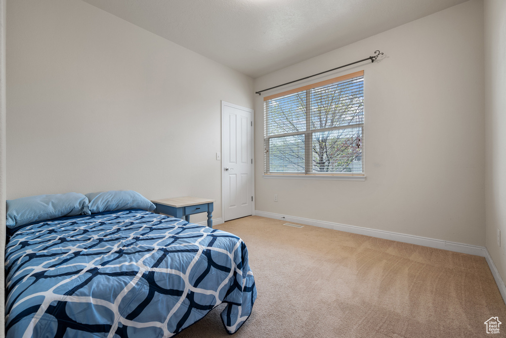 Bedroom with baseboards and light colored carpet