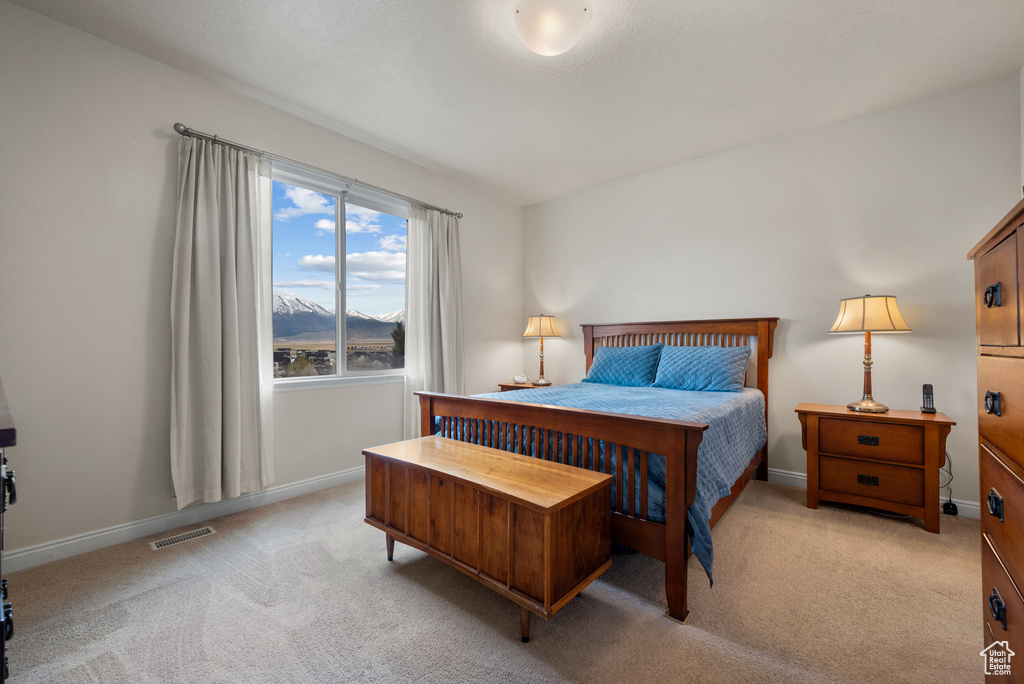 Bedroom with a mountain view, visible vents, baseboards, and light carpet