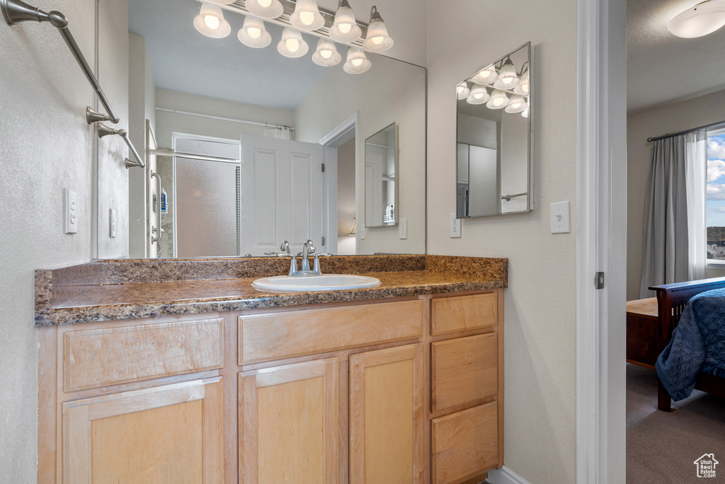 Ensuite bathroom featuring vanity, ensuite bath, and a shower with door