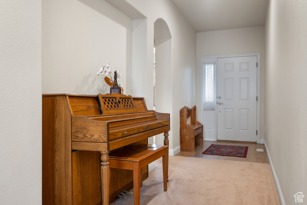 Entrance foyer with arched walkways, light colored carpet, and baseboards