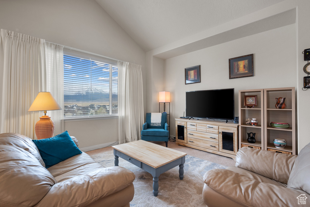Living room with high vaulted ceiling, light carpet, and baseboards