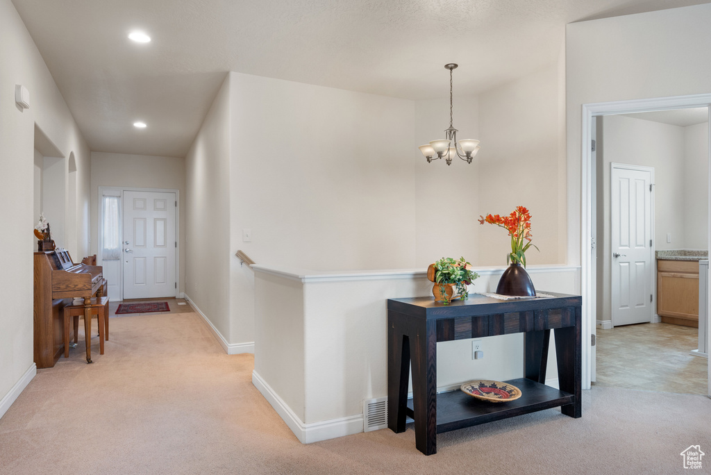 Hall featuring baseboards, recessed lighting, a notable chandelier, and light carpet