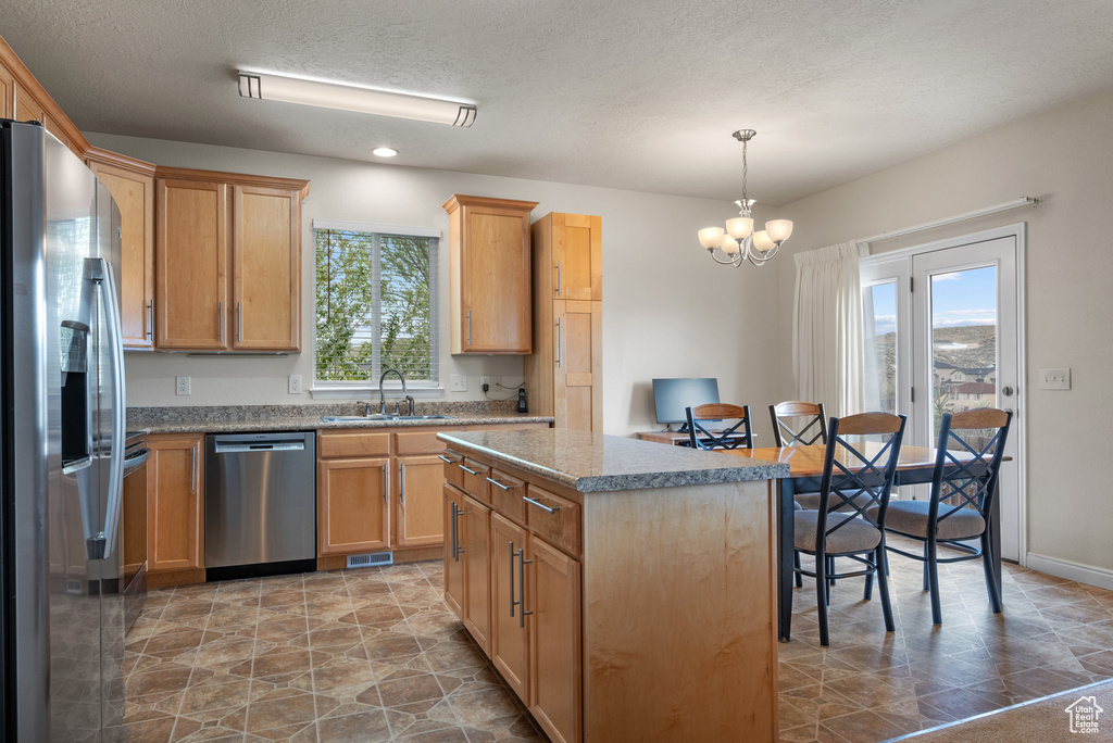 Kitchen with an inviting chandelier, stainless steel appliances, a center island, a sink, and visible vents