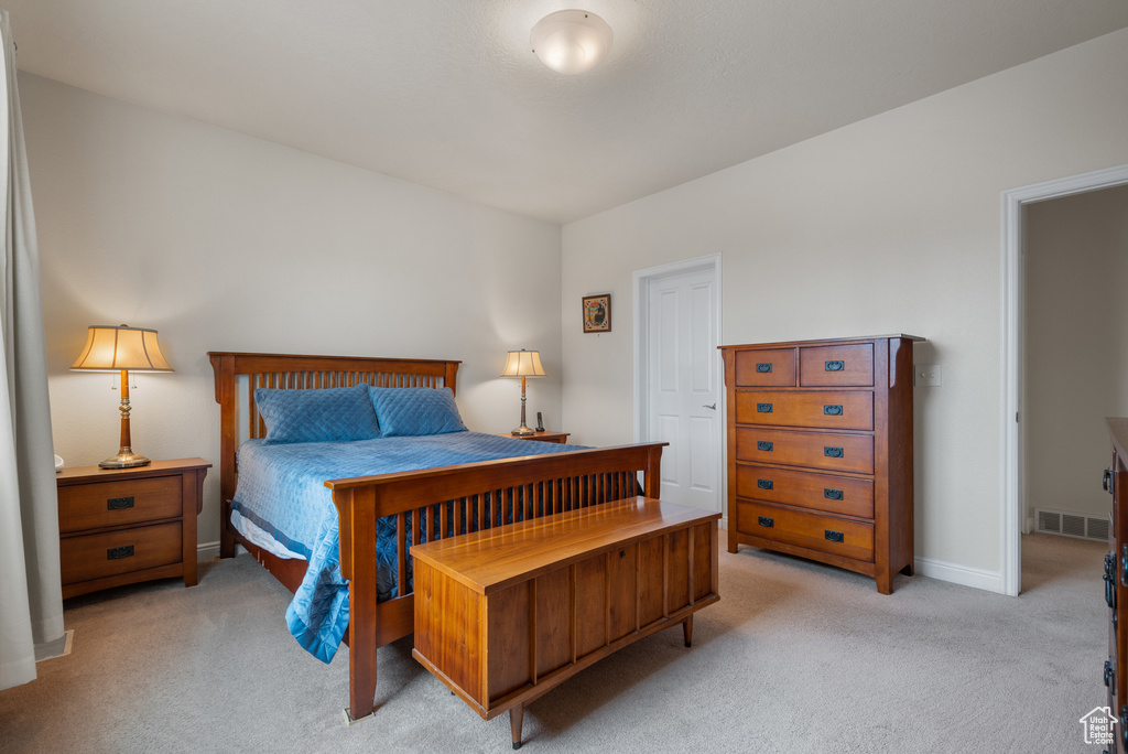 Bedroom with visible vents, light carpet, and baseboards