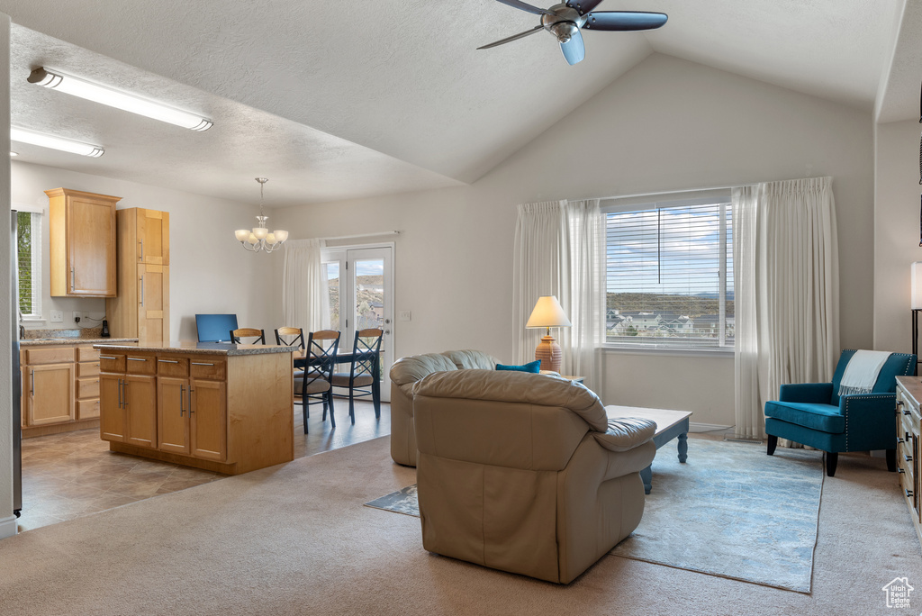 Living area featuring lofted ceiling, light carpet, and ceiling fan with notable chandelier
