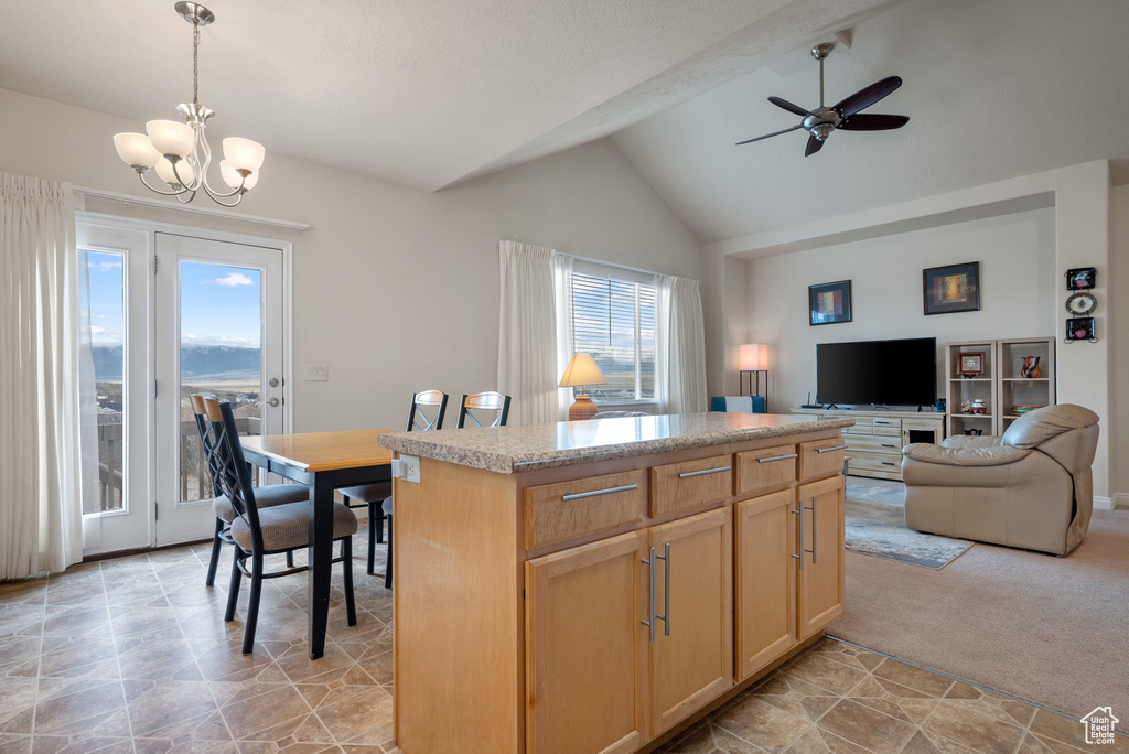 Kitchen featuring decorative light fixtures, a kitchen island, light countertops, open floor plan, and ceiling fan with notable chandelier