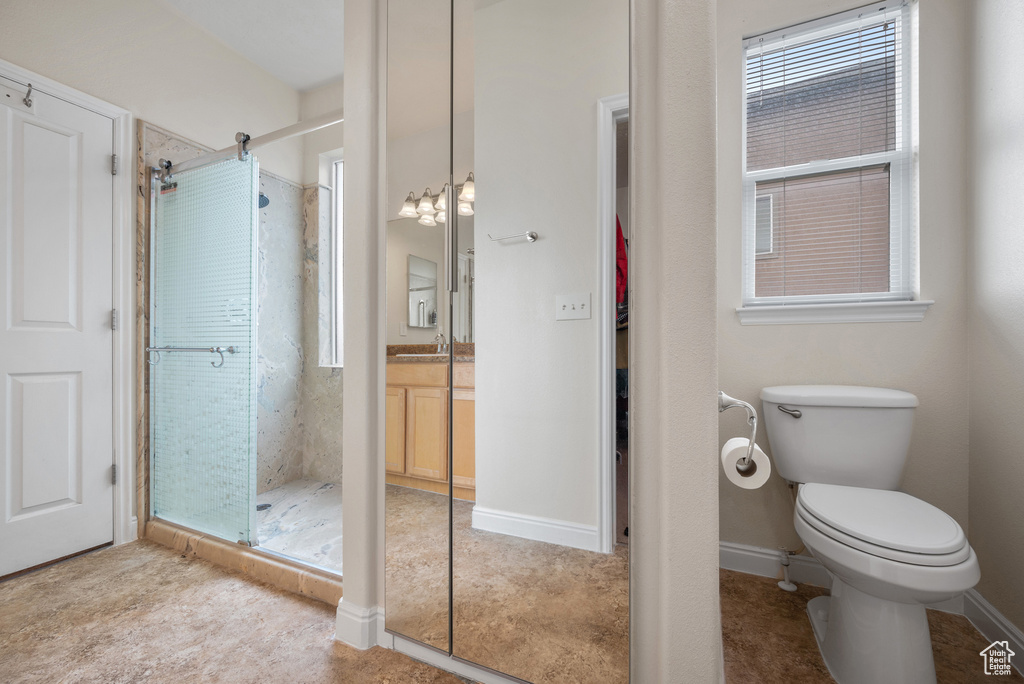 Bathroom featuring a shower stall, toilet, and vanity