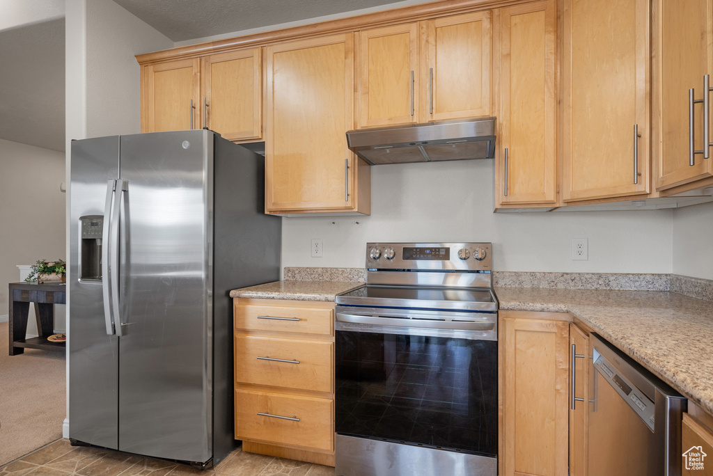 Kitchen featuring appliances with stainless steel finishes, light brown cabinetry, and under cabinet range hood