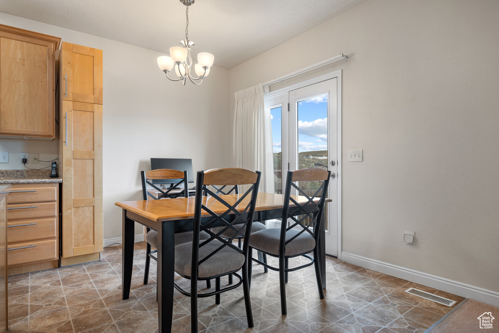 Dining room featuring stone finish flooring, an inviting chandelier, visible vents, and baseboards
