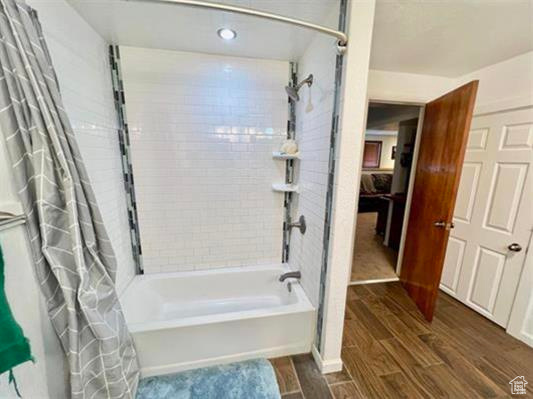 Bathroom featuring recessed lighting, shower / bathtub combination with curtain, and wood finished floors